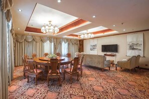 A hotel dining room with a round table, chairs, a sofa, and a television. - Fortune Hotel (Mangshi)