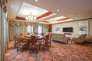 Un comedor de hotel con una mesa redonda, sillas, un sofá y un televisor.