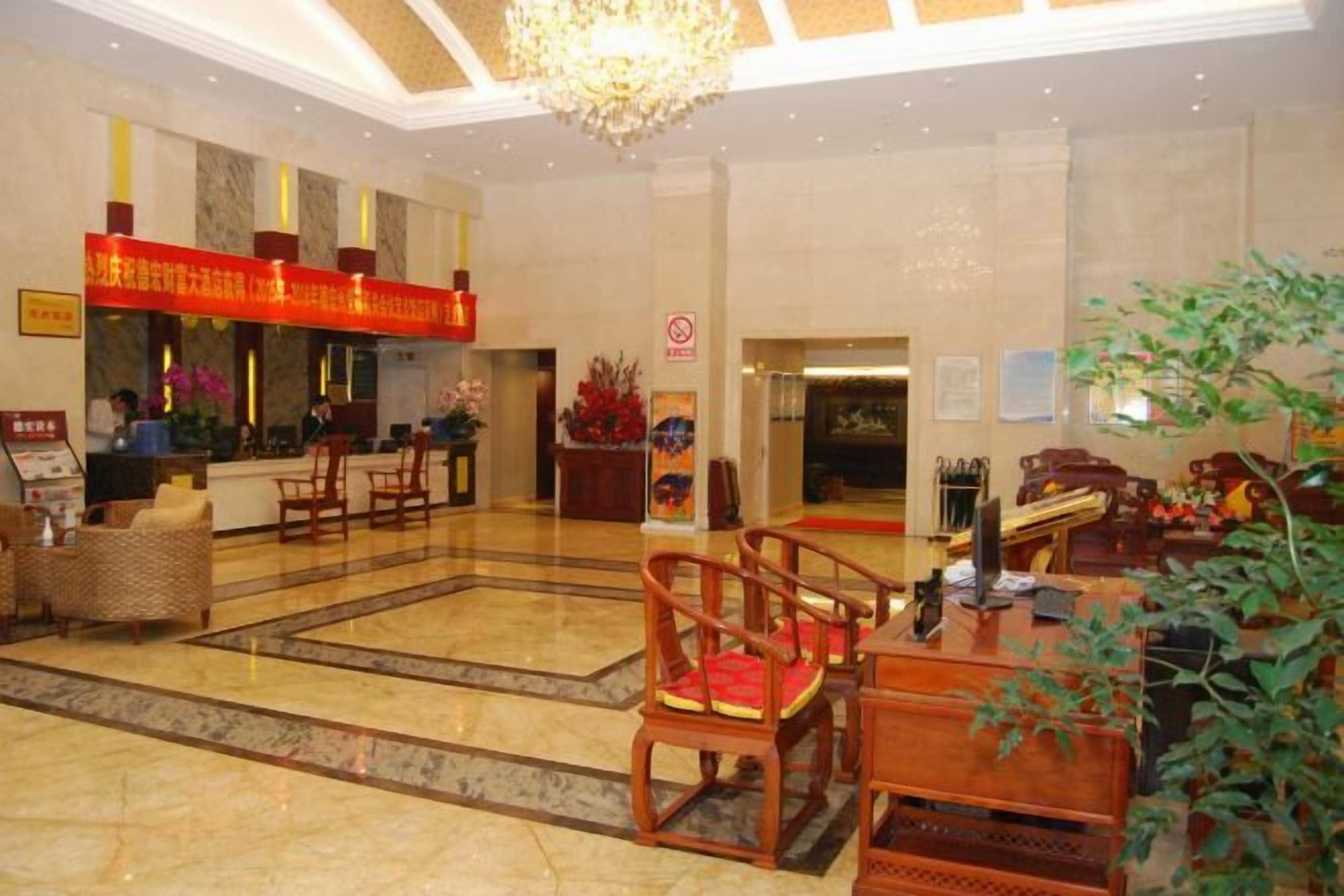 Um saguão de hotel com balcão de recepção, área de estar e um lustre.