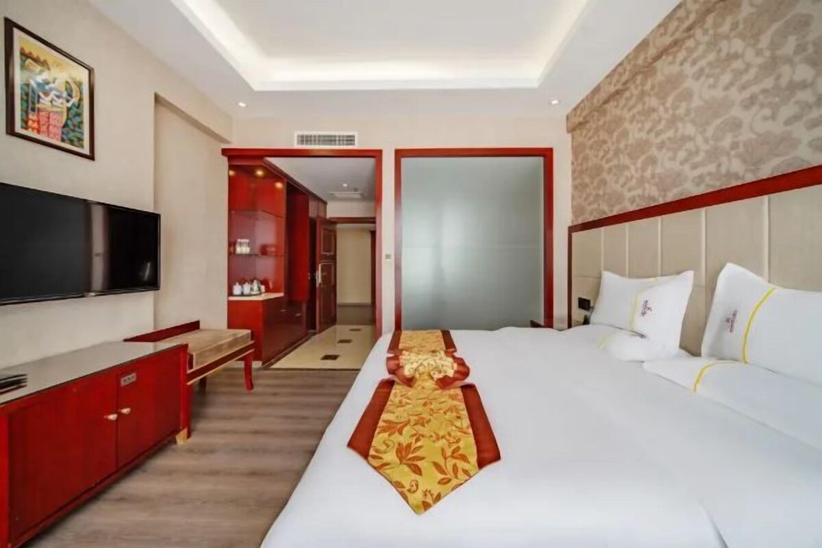 A hotel room with a bed, a TV, a desk, and a wardrobe.