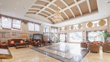 A spacious lobby with a high ceiling, a grand staircase, and comfortable seating areas.