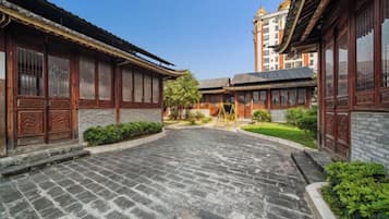 A courtyard with traditional architecture, stone paving, and greenery.
