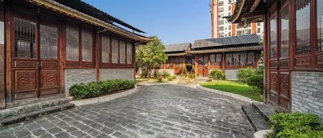 A courtyard with traditional architecture, stone paving, and greenery.