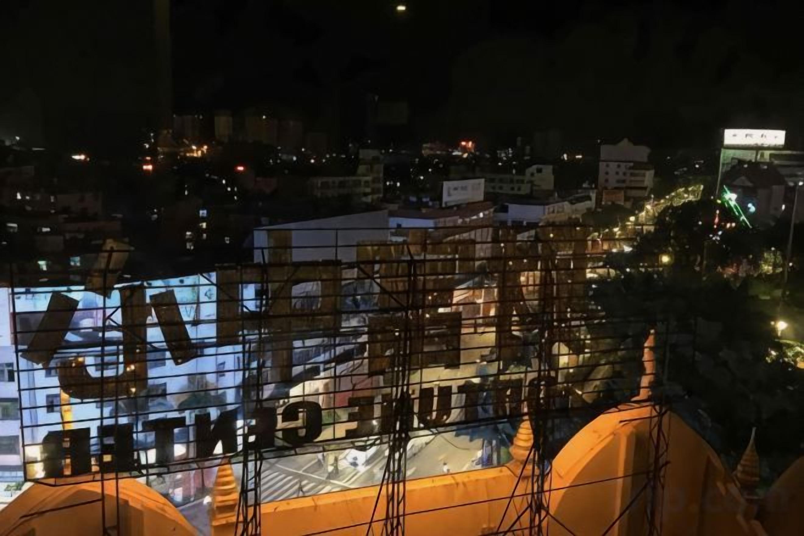 A nighttime view of a cityscape with a building featuring a large illuminated sign.