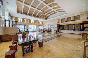 A spacious lobby with a high ceiling, a reception desk, and a seating area with a table and chairs.