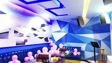 A room with a geometric wall design, a seating area with pink balloons, and a table with various items.