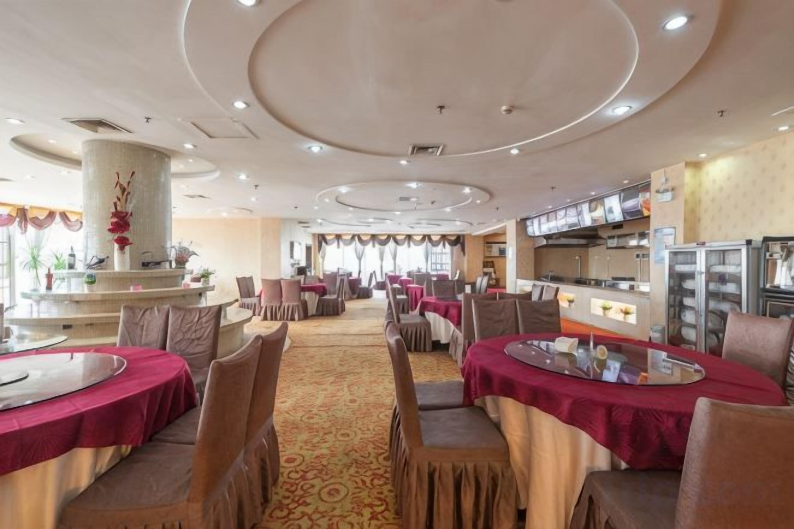 A hotel dining area with round tables, chairs, and a central column.