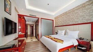 A hotel room with a large bed, a TV, a desk, and a wardrobe. - Fortune Hotel (Mangshi)