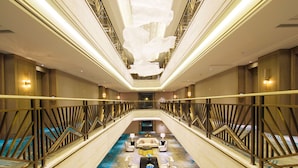 A hotel lobby with a central seating area, a staircase, and a ceiling with hanging decorations.