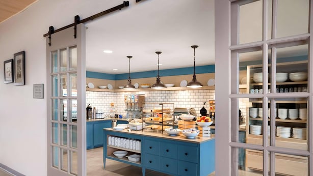 Une cuisine avec un îlot central bleu, des armoires blanches et des luminaires suspendus.