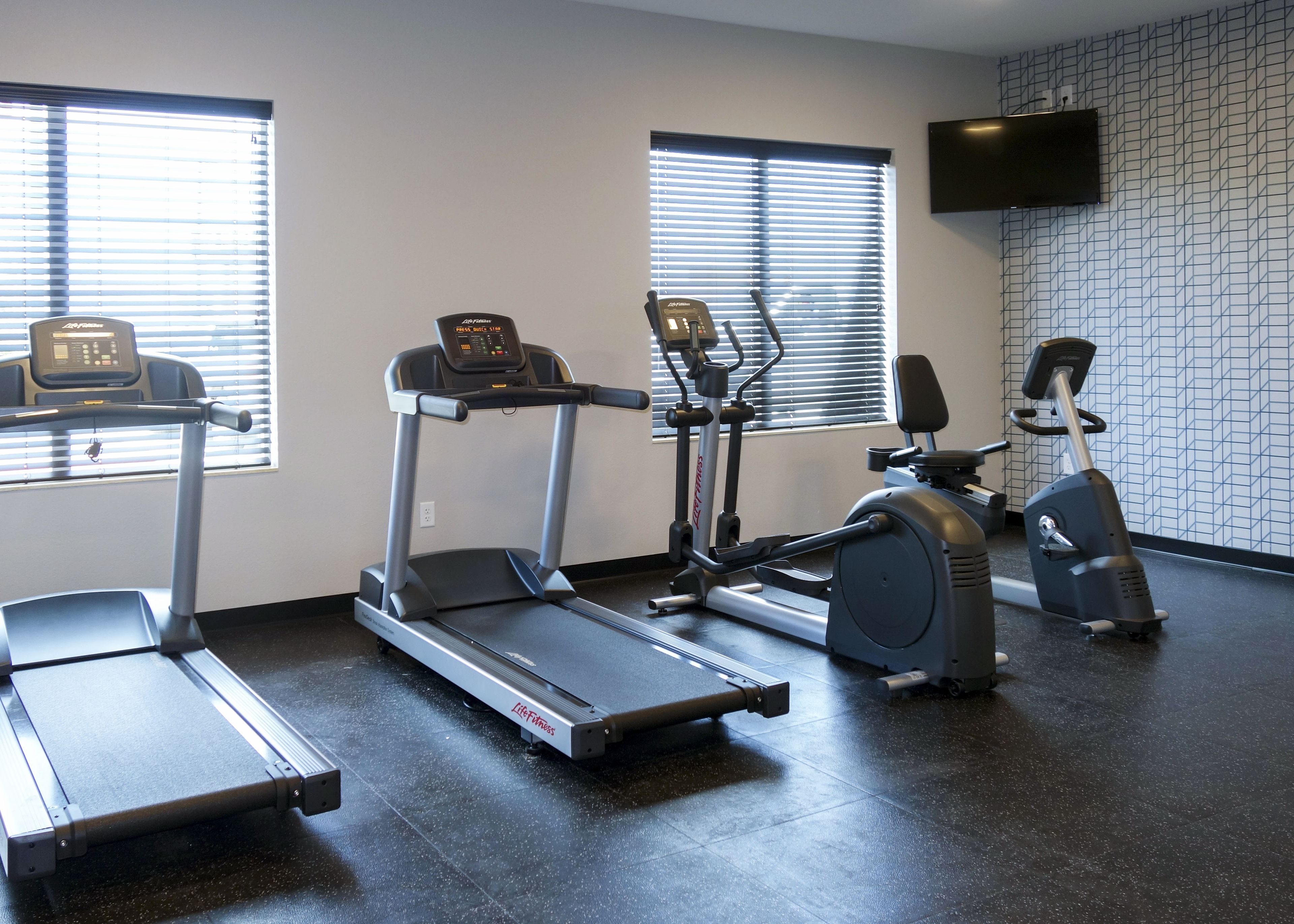 Une salle de sport équipée de tapis de course, d’un vélo elliptique et d’un vélo d’appartement.