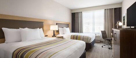 A hotel room with two beds, a desk, a chair, a TV, and a large window with curtains.