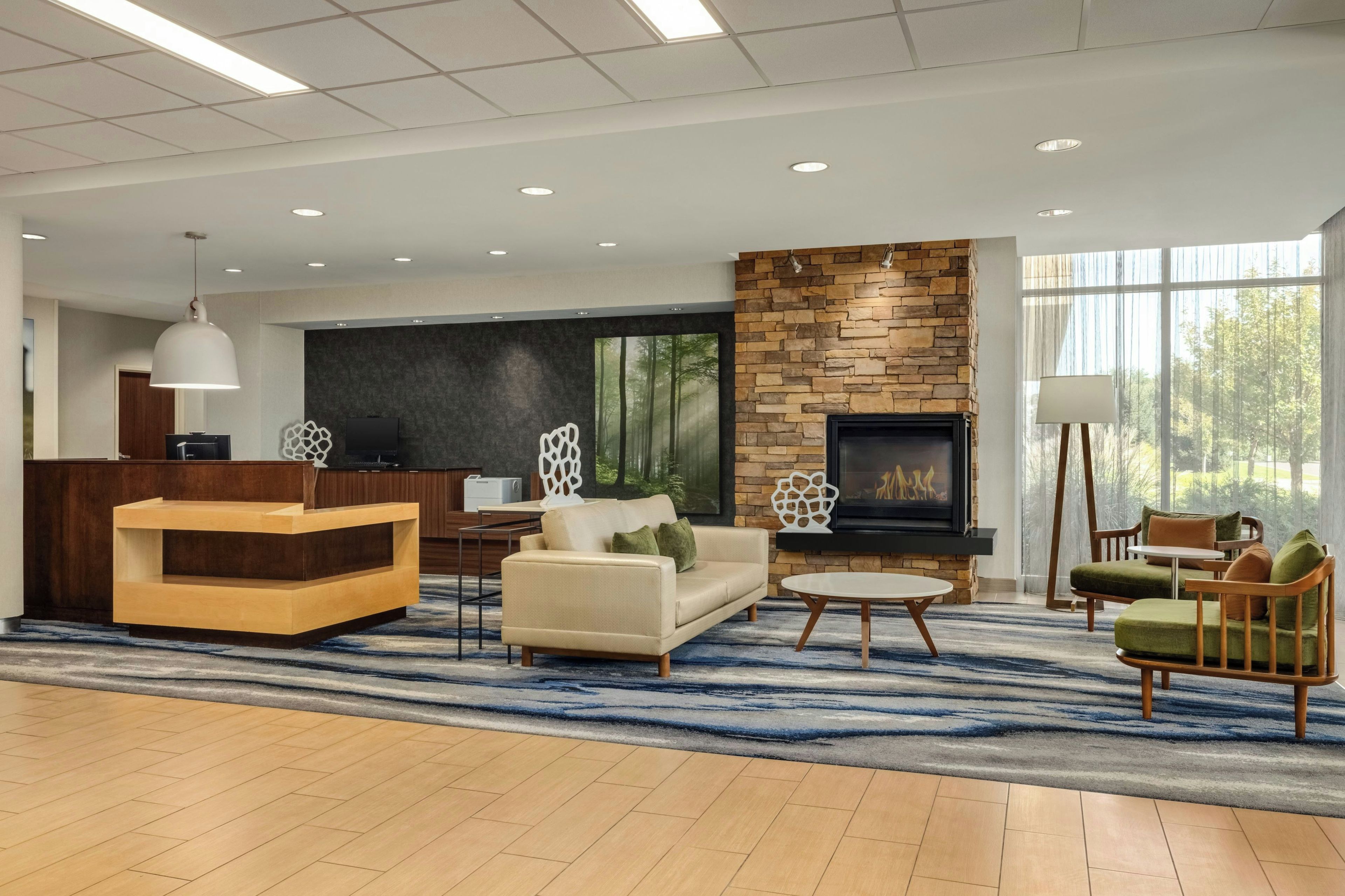 A modern living room with a fireplace, seating area, and a large window providing a view of the outdoors.
