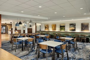 Un restaurante moderno con varias zonas de comedor, incluidas mesas y cabinas, y diferentes lámparas de techo.