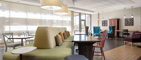 A modern lounge area with a sofa, chairs, a table, and pendant lighting.