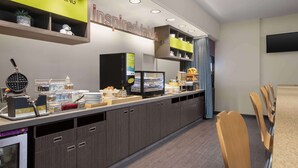 A breakfast bar with a 'Good Morning' sign, a 'Inspired Table' sign, and a variety of food and drink options.