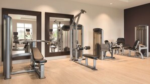 A gym with various exercise machines, a bench, and a mirror.