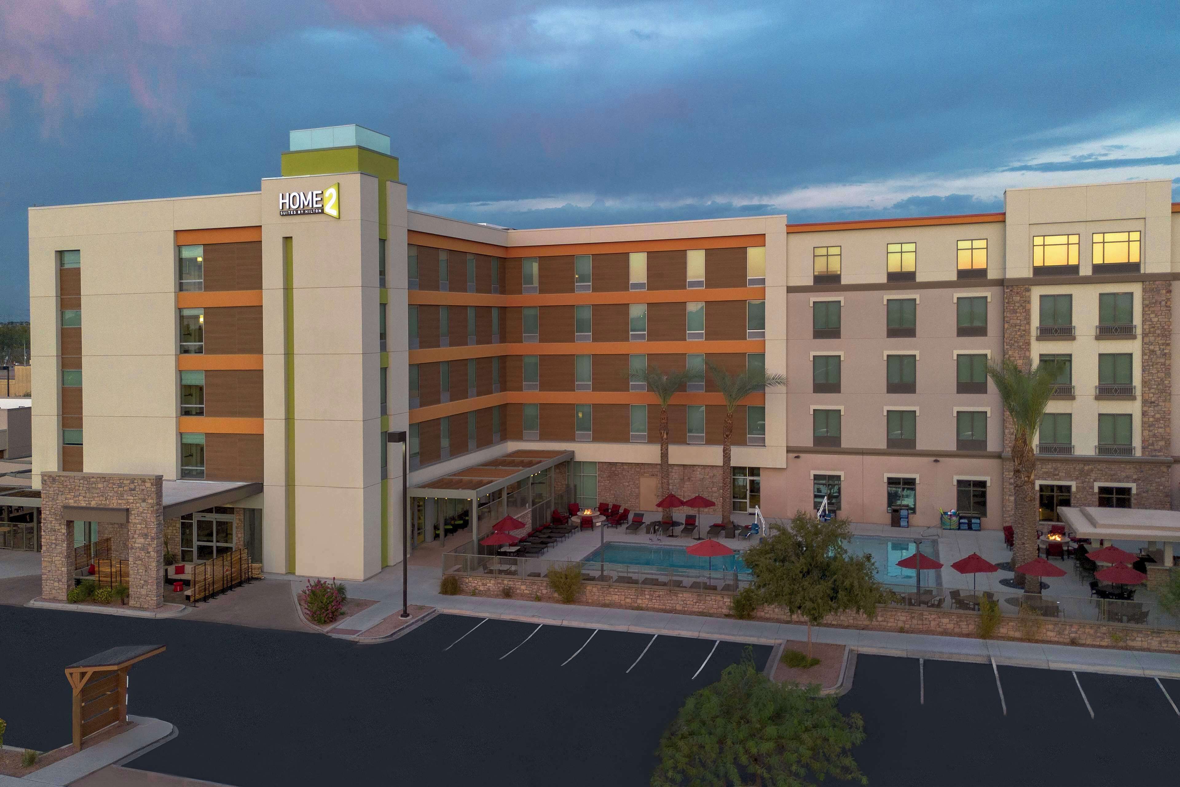 A multi-story hotel with a pool area, outdoor seating, and a parking lot.