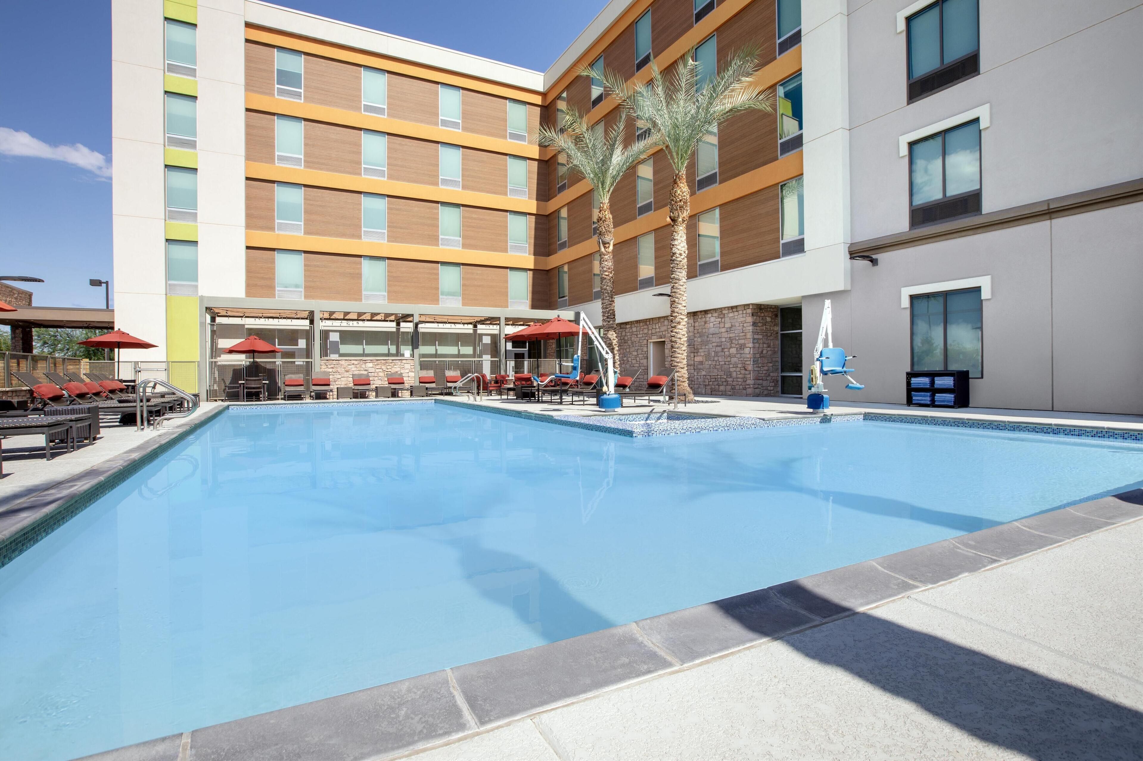 Um hotel moderno com piscina, área de estar externa e palmeiras.