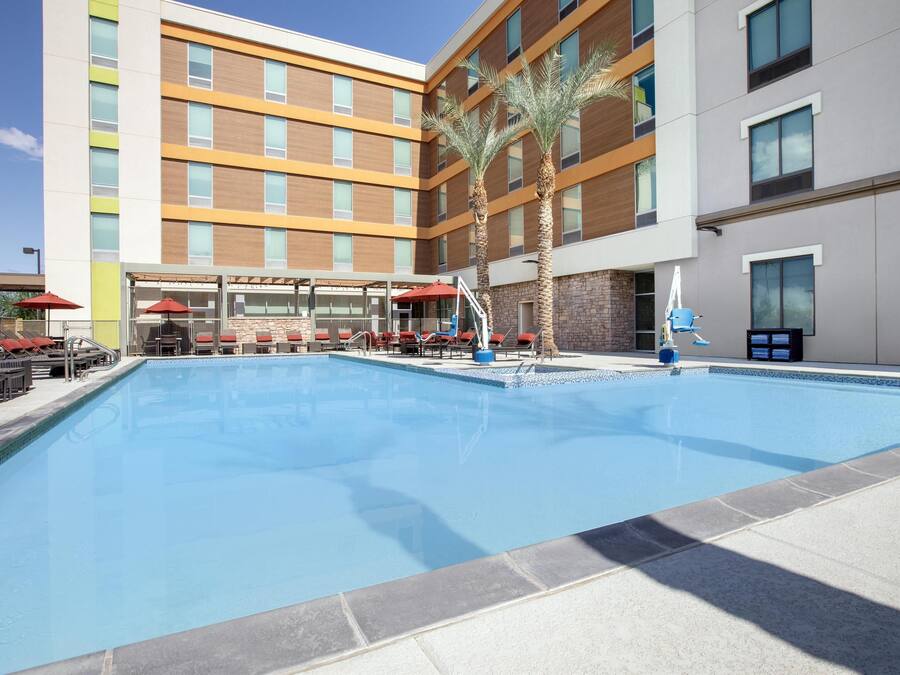 Um hotel moderno com piscina, área de estar externa e palmeiras.