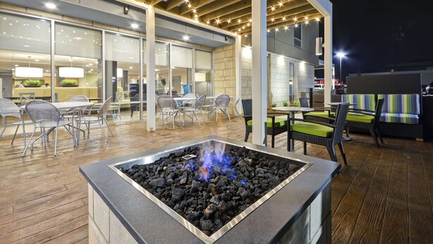 An outdoor patio with a fire pit, tables, chairs, and a covered seating area.