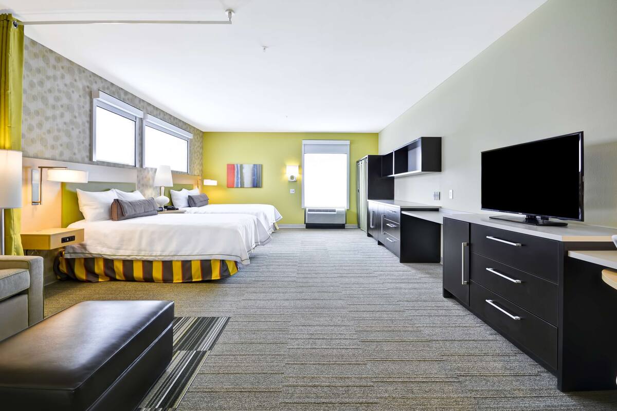 Habitación de hotel con una cama grande, un escritorio con televisor y vistas a la ciudad.