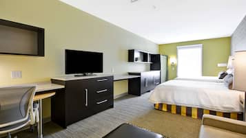 Ein Hotelzimmer mit Bett, Schreibtisch, Stuhl, Fernseher und einem Fenster.