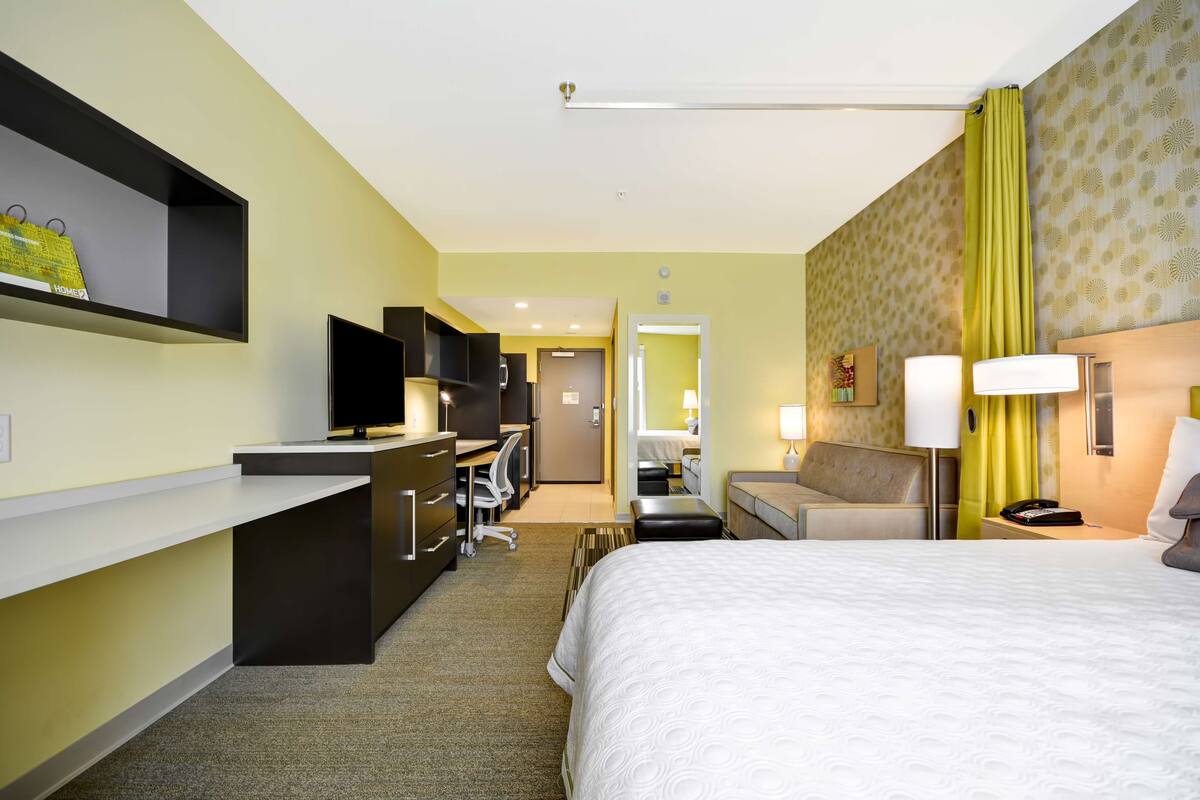Una habitación de hotel con cama, escritorio, silla y televisión.