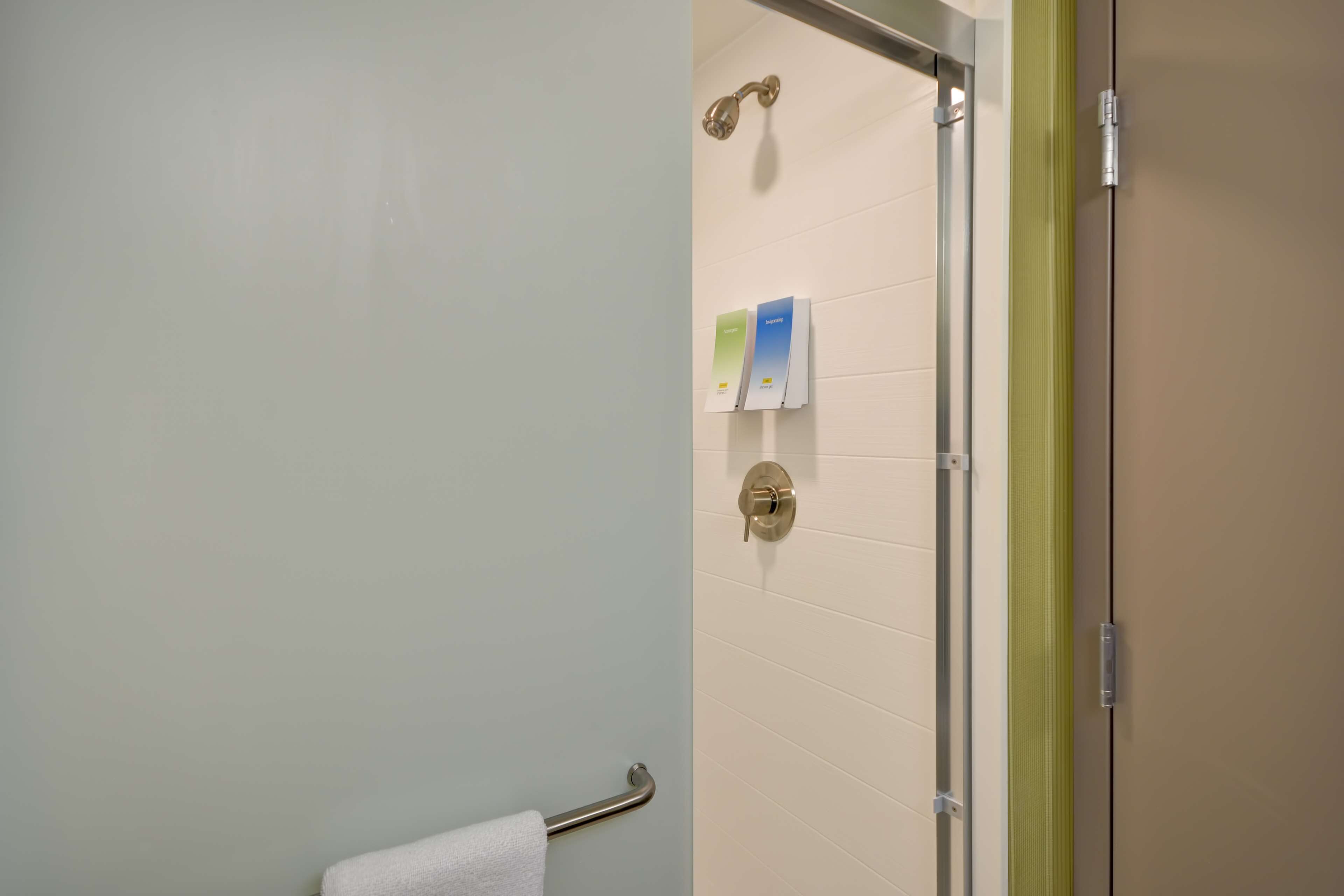 Un baño con mampara de vidrio, un perchero y un panel de control en la pared.