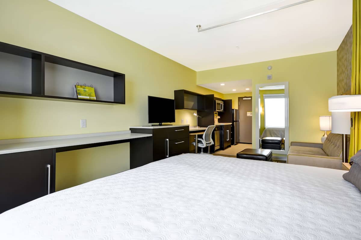 Una habitación de hotel con cama, escritorio, silla y kitchenette.