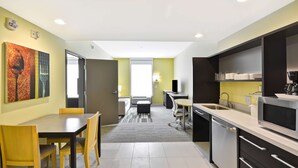 A modern kitchen with a dining area, featuring a large table, chairs, and a microwave.
