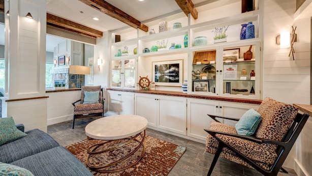 Een moderne keuken met witte kastjes, een houten plafond en diverse decoratieve items op planken.
