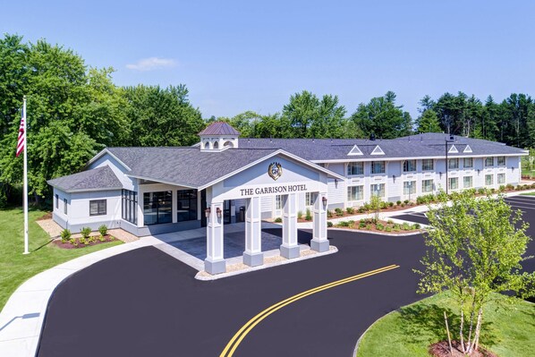 A hotel with a modern design, featuring a prominent entrance with a covered area and a flagpole.