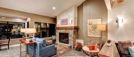 A living room with a fireplace, seating, and a view of the outside.