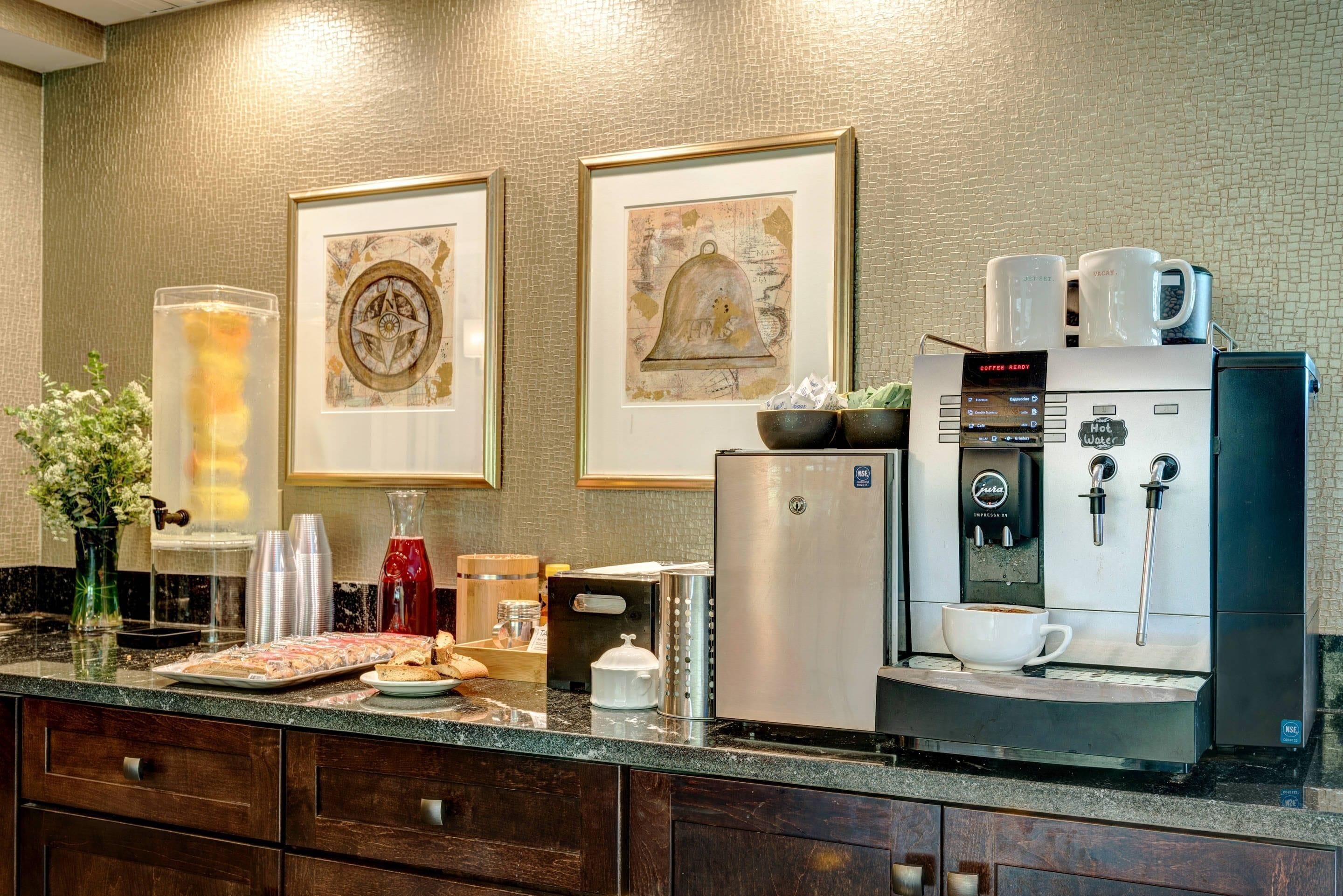 A kitchen with a coffee machine, framed artwork, and various kitchen appliances.