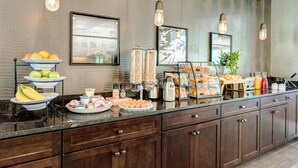 Een ontbijtbuffet met diverse etenswaren, een koffiehoek en ingelijste kunst aan de muur.