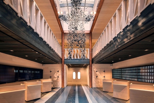 A spacious lobby with a central staircase, wooden reception desks, and a large chandelier. - Moxy NYC Times Square (New York)