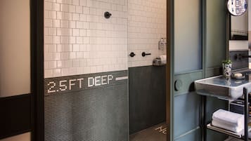 Een badkamer met witte en donkere tegels, een wastafel met spiegel en een handdoekhouder.