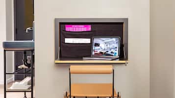 A laptop on a shelf with a sign about upcoming events, a foldable chair, and a shelf with towels.