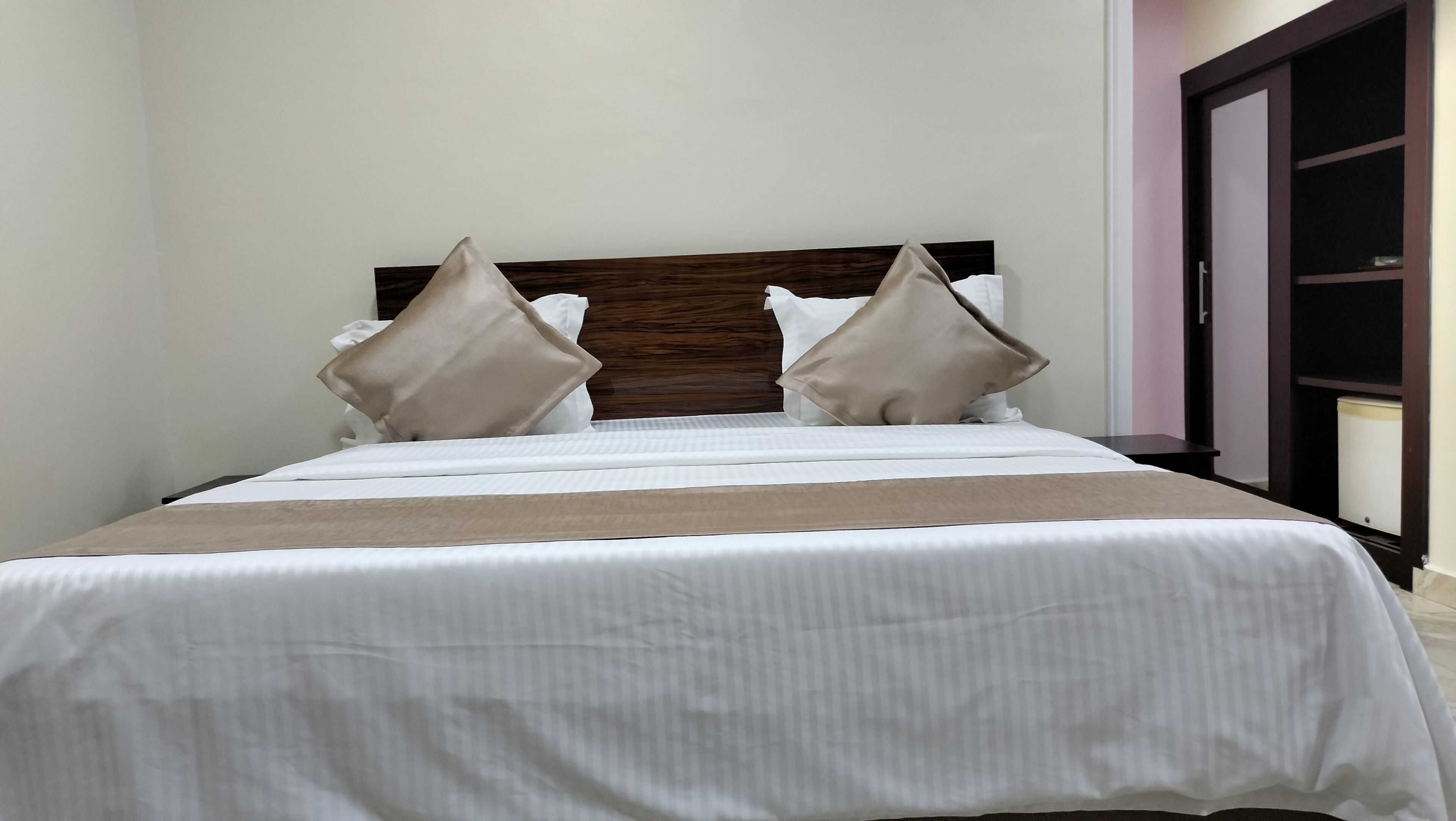 A neatly made bed with a wooden headboard, two pillows, and a white bedspread.