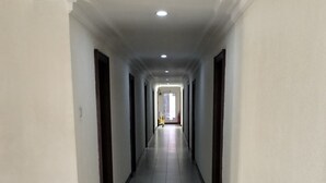 En lång, smal hall med vita väggar och ett klinkergolv.
