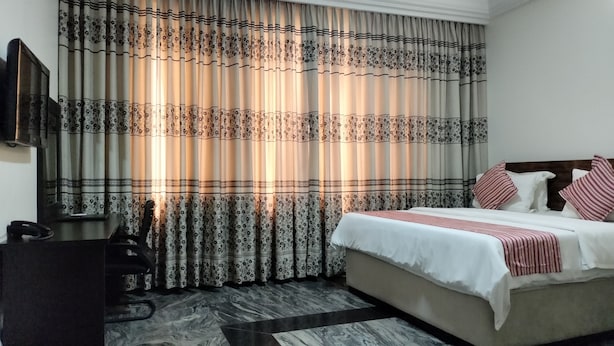 Ett hotellrum med en säng, ett skrivbord och en stol.