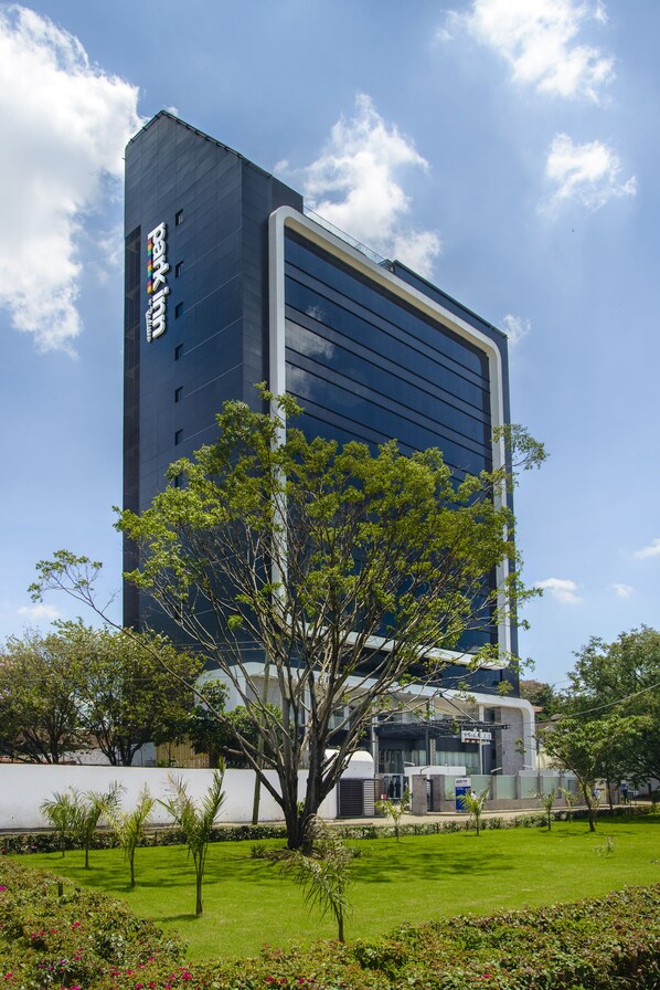 A modern building with a large glass facade and a sign indicating it is a hotel. - Park Inn by Radisson Nairobi Westlands (Nairobi)