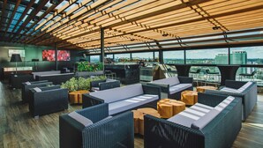 Un salon sur le toit, aménagé avec des meubles en osier, des tables en bois et offrant une vue sur la ville.
