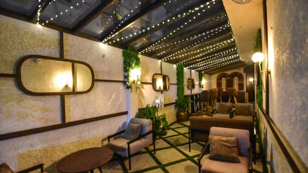 Un'accogliente area relax con divani e tavolini, uno specchio decorativo e luci a stringa sul soffitto.