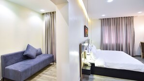 Una camera d'albergo moderna con un letto, un divano e un comodino.