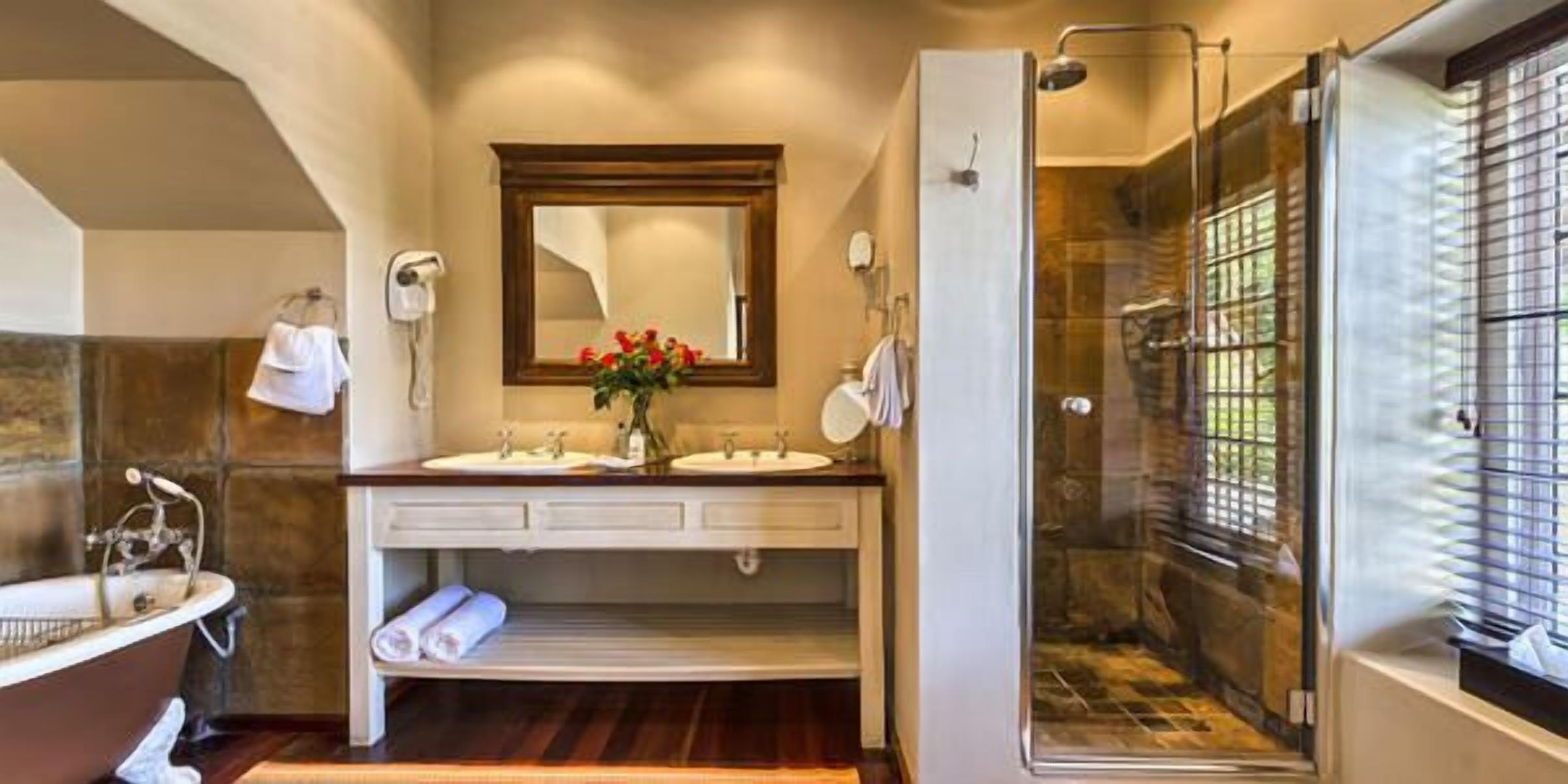 A bathroom with a bathtub, two sinks, a mirror, and a shower area.