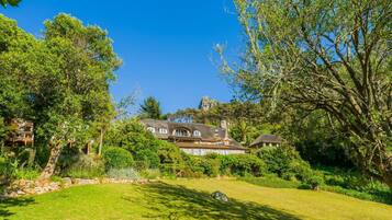 A large house with a thatched roof, surrounded by lush greenery and trees.