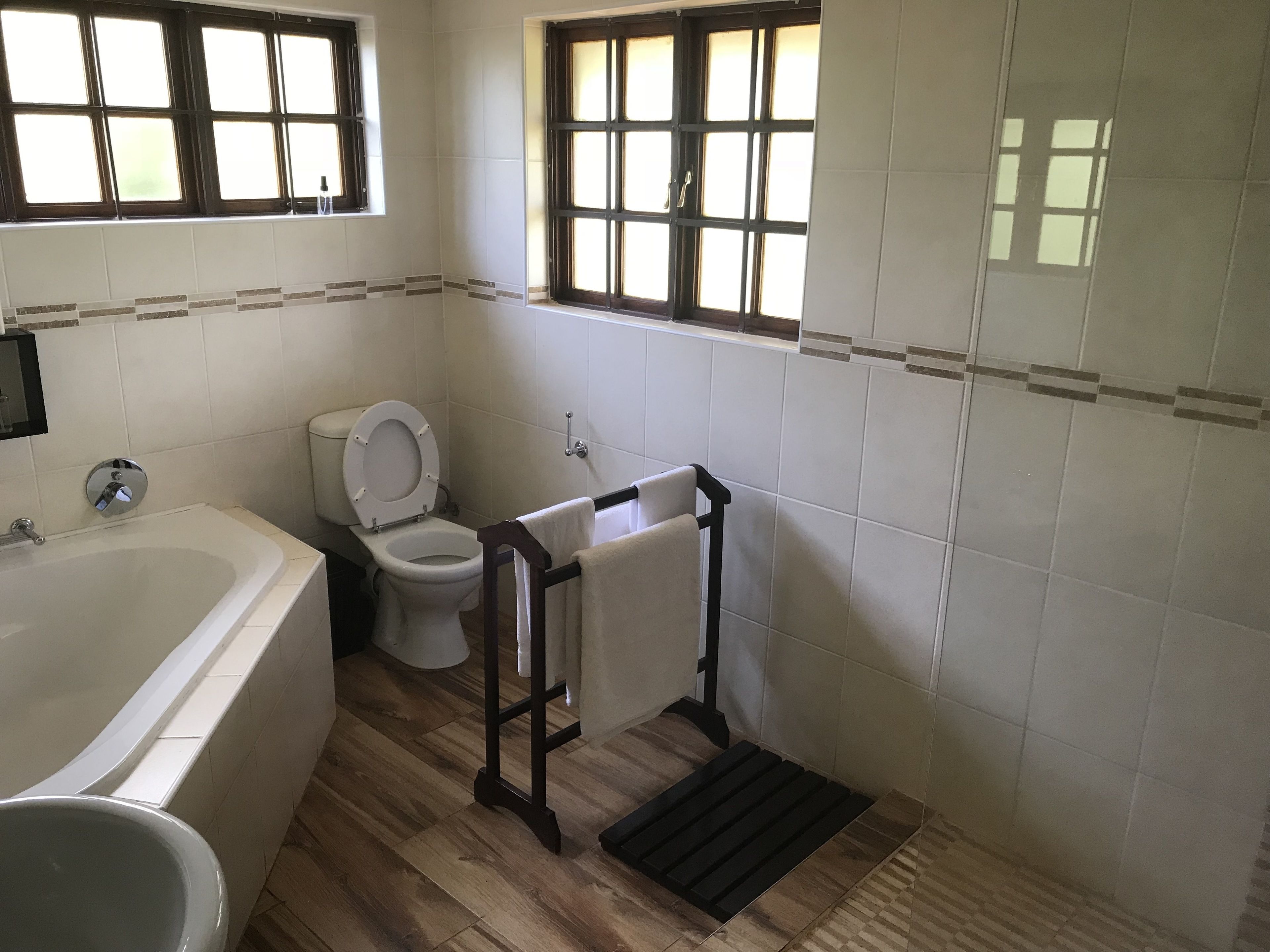 Een badkamer met een bad, toilet en raam.