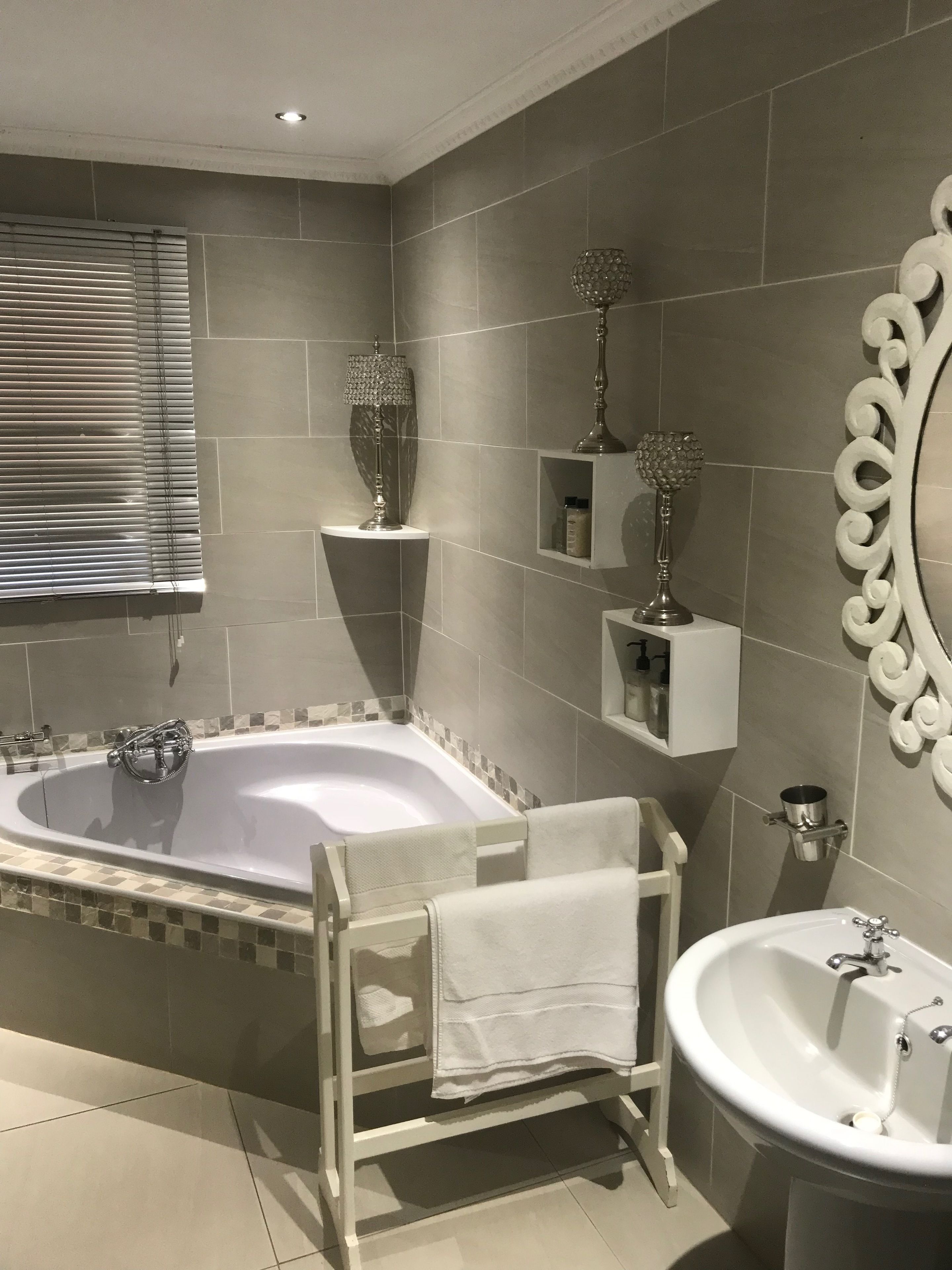 A modern bathroom with a large bathtub, a pedestal sink, and a decorative mirror.